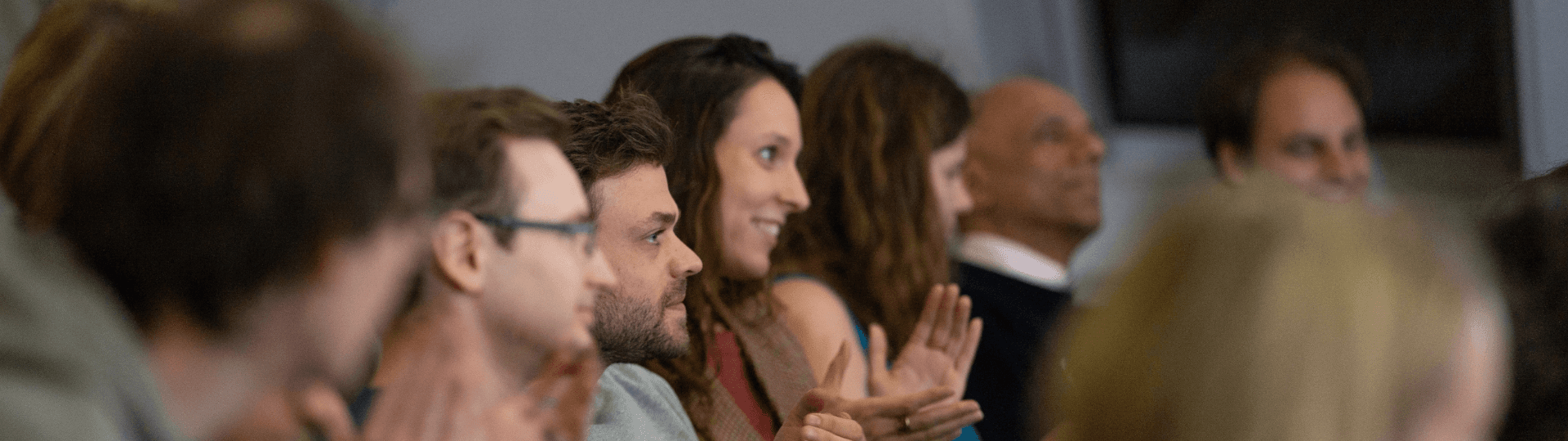 Smiling audience members applauding at a workshop
