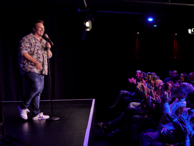 Benjamin on stage with a microphone, the audience applauding