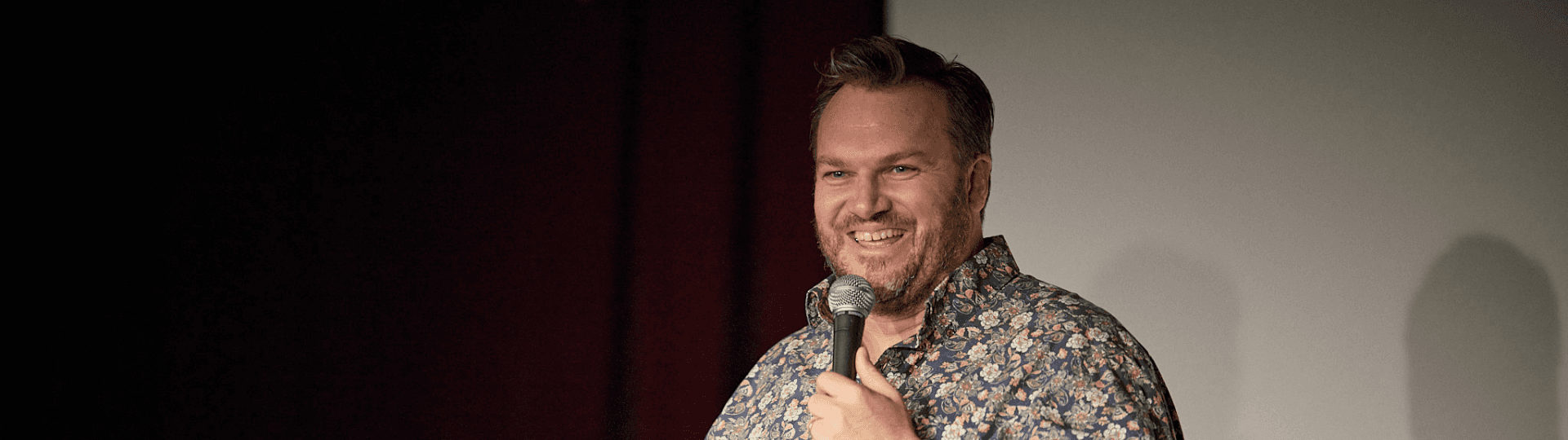 Benjamin smiling on stage with a microphone